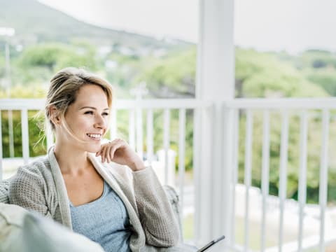 Frau sitzt am Fenster und ist glücklich