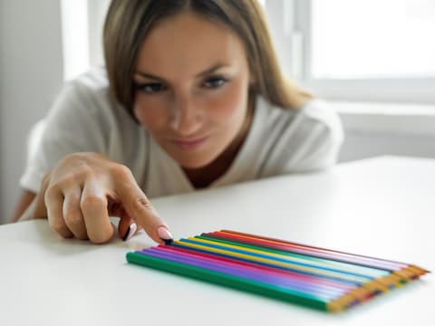 Frau schiebt mehrere Bleistifte in die exakt gleiche Position
