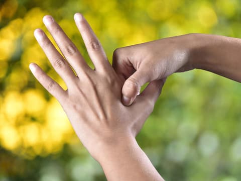 Frau drückt Akupressurpunkt zwischen Daumen und Zeigefinger
