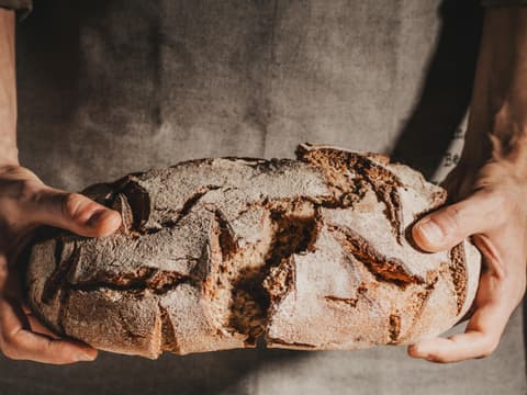 Mann bricht ein frischgebackenes Brot durch