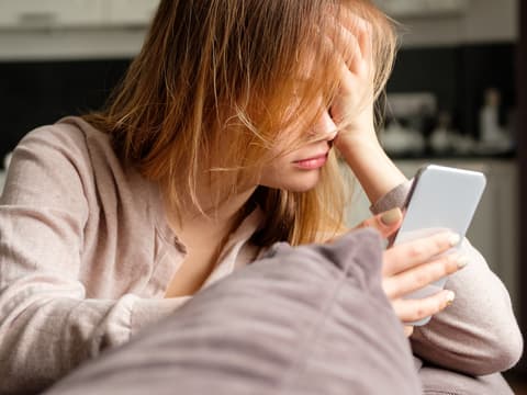 Frau schaut traurig auf Ihr Handy