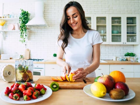 Frau schneidet Obst für einen Smoothie