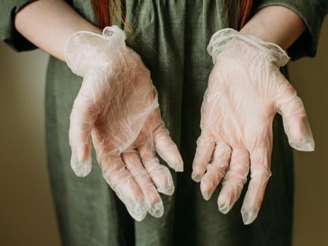 Ärztin hält in Latexhandschuhe verpackte Hände mit den Handflächen nach vorn in die Kamera