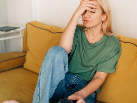 Unglückliche Frau sitzt auf Sofa