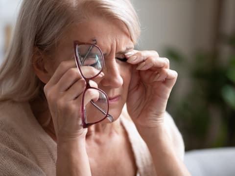 Frau reibt sich aufgrund von Beschwerden über die Augen