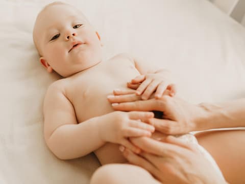 Mutter massiert sanft die Bauchschmerzen beim Baby weg.