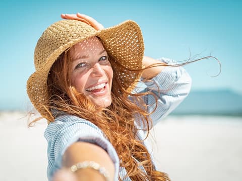 Frau mit Sonnenhut am Strand
