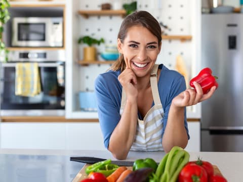 Frau in der Küche hält Paprika in den Händen