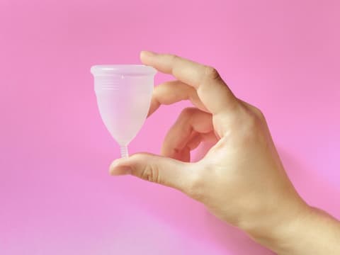 Frau hält Menstruationstasse in der Hand