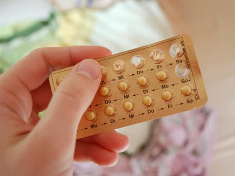 Frau hält Blister mit Antibabypille in der Hand