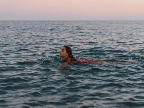 Frau schwimmt beim Sonnenuntergang im Meer