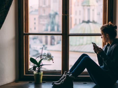 Frau mit sozialer Phobie sitzt vor dem Fenster und guckt nach draußen