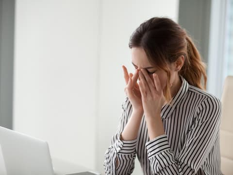 Frau vor Laptop reibt sich trockene Augen