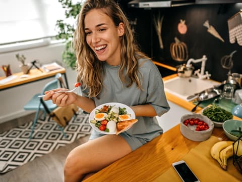 Junge Frau isst gesunden Salat in ihrer Küche