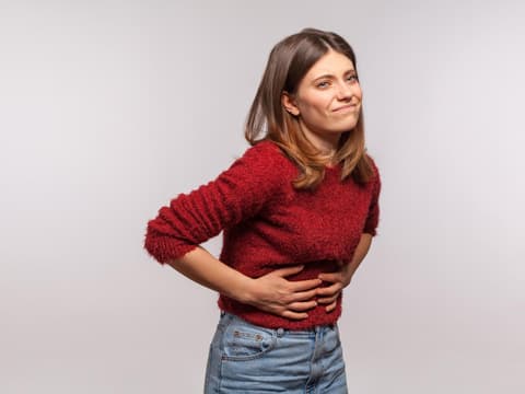Frau hält sich den Bauch, weil sie Hunger hat