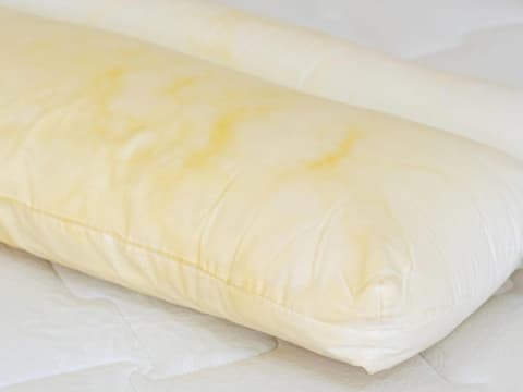 Gelbes Kissen auf dem Bett 