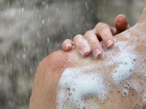 Frau unter der Dusche schäumt sich ein