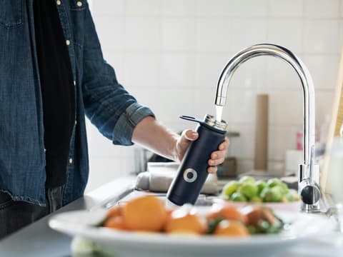 Mann füllt Flasche am Wasserhahn auf