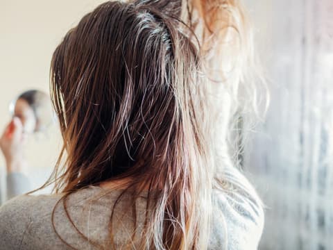 Frau begutachtet ihre fettigen Haare