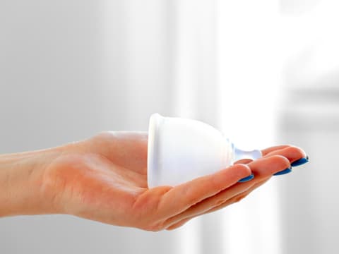 Frau hält Menstruationstasse in der Hand