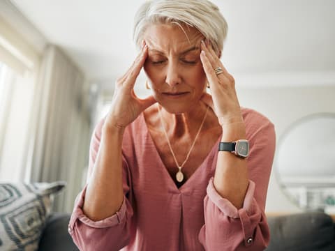 Frau hält sich den schmerzen Kopf