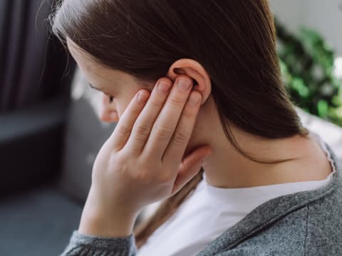 Frau hält sich das schmerzende Ohr