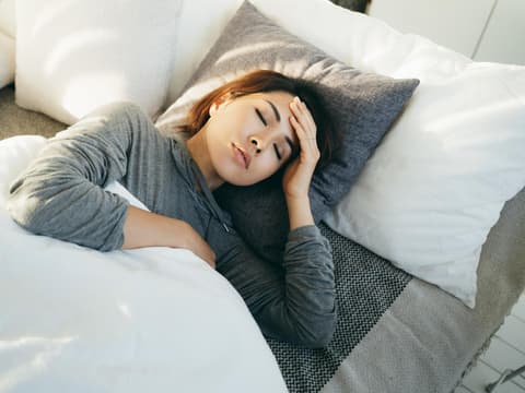 Frau liegt mit Schwindel im Bett