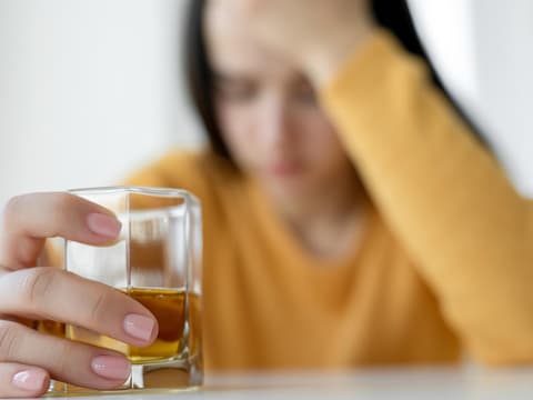 Verzweifelte Frau mit einem Glas Alkohol in der Hand