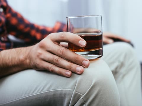 Männerhände mit einem Glas Whiskey in der Hand