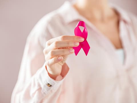 Frau hält pinke Schleifen in den Händen