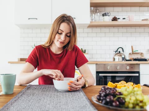 Frau isst Frühstück in der Küche