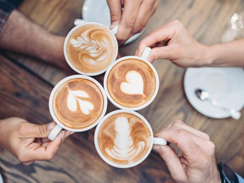 Hände, die mit Kaffee anstoßen