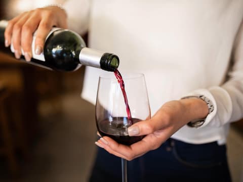Frau schenkt sich ein Glas Wein ein