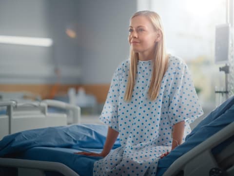 Frau sitzt auf Krankenhausbett