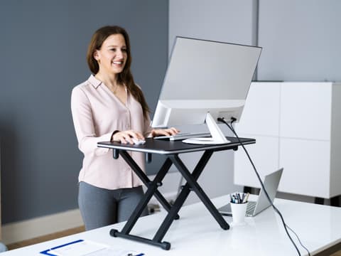 Frau steht vorm Schreibtisch und arbeitet