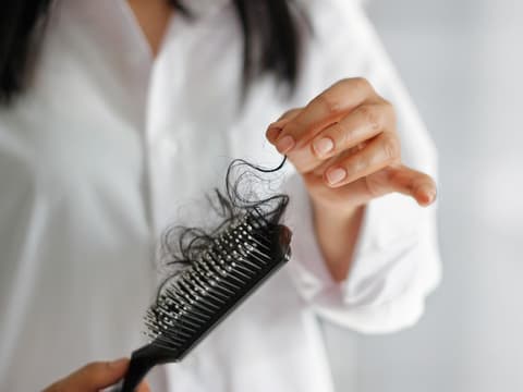Frau mit Bürste, in der ein Haarbüschel steckt