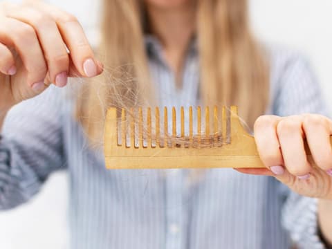 Frau hat viele Haare in der Haarbürste