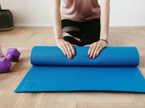 Frau rollt Sportmatte zusammen