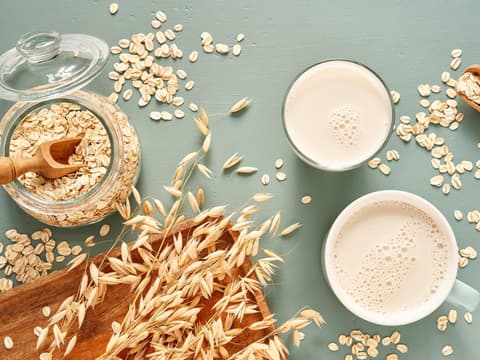 Hafermilch in einem Glas und einer Tasse