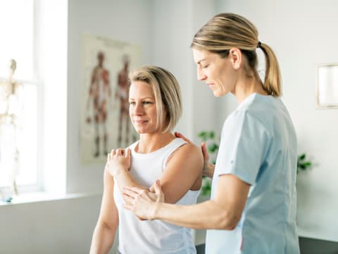 Frau macht Übung mit Physiotherapeutin