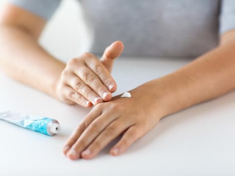 Frau cremt ihren Handrücken ein