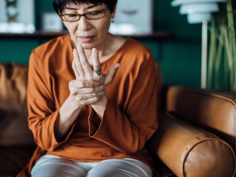 Frau hält sich schmerzende Hand