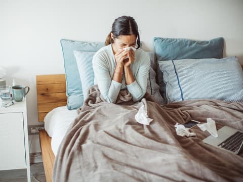 Frau mit Grippe im Bett