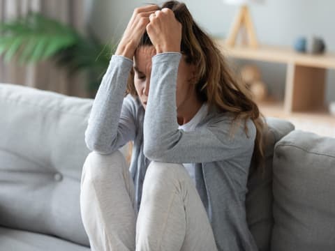 Frau sitzt verzweifelt auf dem Sofa