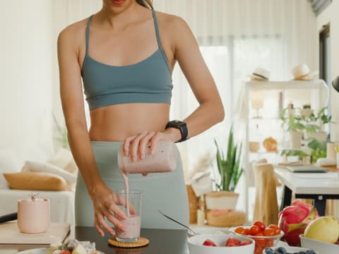 Frau im Sportoutfit macht sich Proteinshake