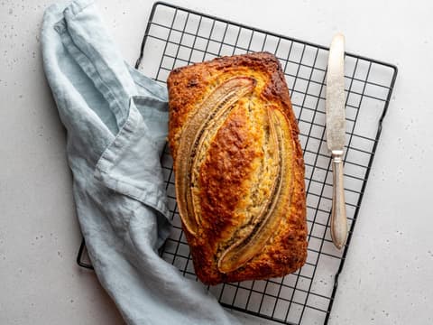 Bananenbrot angerichtet mit einem Messer auf einem Rost