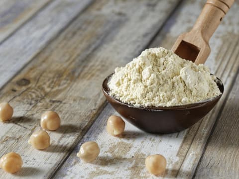 Löffel mit Kichererbsenmehl neben vereinzelten Kichererbsen