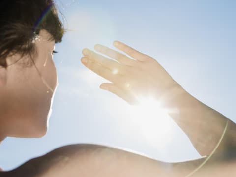 Eine Frau schützt sich mit der Hand vor der Sonne 