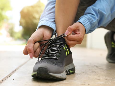 Eine Frau bindet sich die Schuhe zu
