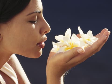 Frau riecht an Blumen